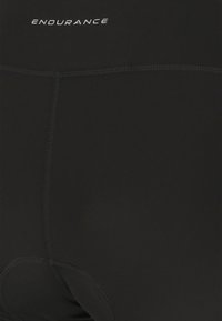 Gros plan sur un cuissard de cyclisme noir avec des coutures visibles et le texte « ENDURANCE » sur la ceinture.