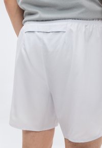 Ανοιχτό γκρι σορτς με ελαστική μέση, πίσω τσέπη και απαλό, ελαφρύ ύφασμα, με ίσια κοπή και χωρίς εμφανή σχέδια.