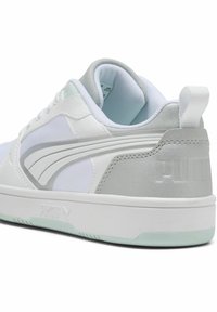 White sneaker with silver accents, featuring a smooth leather upper, textured tongue, and a green-tinged translucent sole.