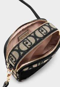 Borsa nera e beige realizzata in tela e pelle, con zip dorate, una tasca interna e dettagli del logo del marchio.