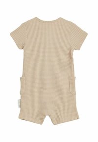 Beige korte mouwen rompert met een gestructureerd wafelpatroon, twee zijzakken en een ronde halslijn. Geschikt voor casual draag.