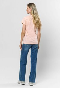 Gaiši rozā īsām piedurknēm t-krekls ar brīvu piegriezumu, apvienots ar augsto vidukļa zilo džinsu, skatīt no aizmugures. Gluda tekstūra.