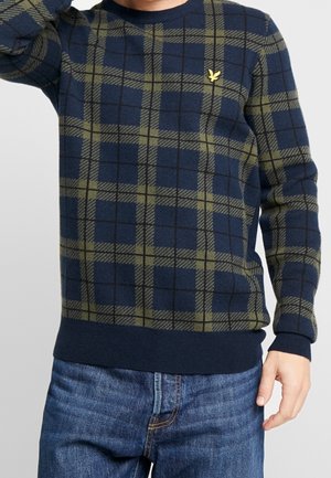 Pull en tricot à carreaux navy et olive avec des manches longues, un col rond, un ourlet côtelé et un petit logo jaune sur la poitrine.