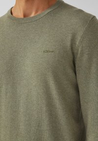 Olivgrüner Strickpullover mit Rundhalsausschnitt, aus weichem Material gefertigt. Verfügt über ein dezentes "s.Oliver"-Logo in passender Stickerei auf der Brust.