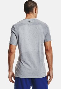 T-shirt de sport gris en tissu texturé, à manches courtes et col rond. Présente un petit logo au dos.