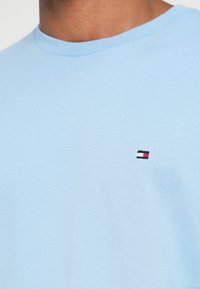 Ανοιχτό μπλε βαμβακερό t-shirt με στρογγυλή λαιμόκοψη. Διαθέτει ένα μικρό κεντημένο λογότυπο σε κόκκινο, λευκό και μπλε χρώμα στην περιοχή του στήθους.