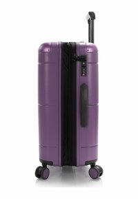 Valigia rigida viola con finitura testurizzata, doppie ruote, manico telescopico e lucchetto a combinazione sulla cerniera.