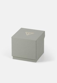 Boîte cadeau texturée gris clair avec un logo triangulaire doré à l'avant, dotée d'un couvercle à rabat et d'un design épuré et minimaliste.