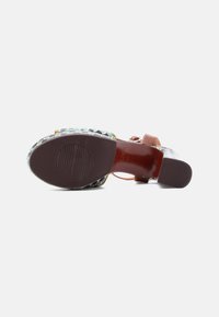 Sandale compensée multicolore avec une semelle à motifs, une lanière en cuir marron et des détails texturés sur la partie supérieure pour la tenue et le style.