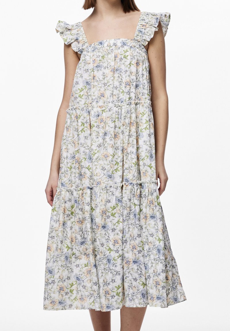 Robe midi sans manches avec bretelles volantées, coupe ample et tissu blanc imprimé de petits motifs floraux pastel.
