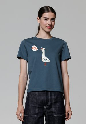 Teal katoenen T-shirt met korte mouwen, met een cartoonvogel en een spraakwolk met het woord "MOM." Losse pasvorm en een ronde hals.