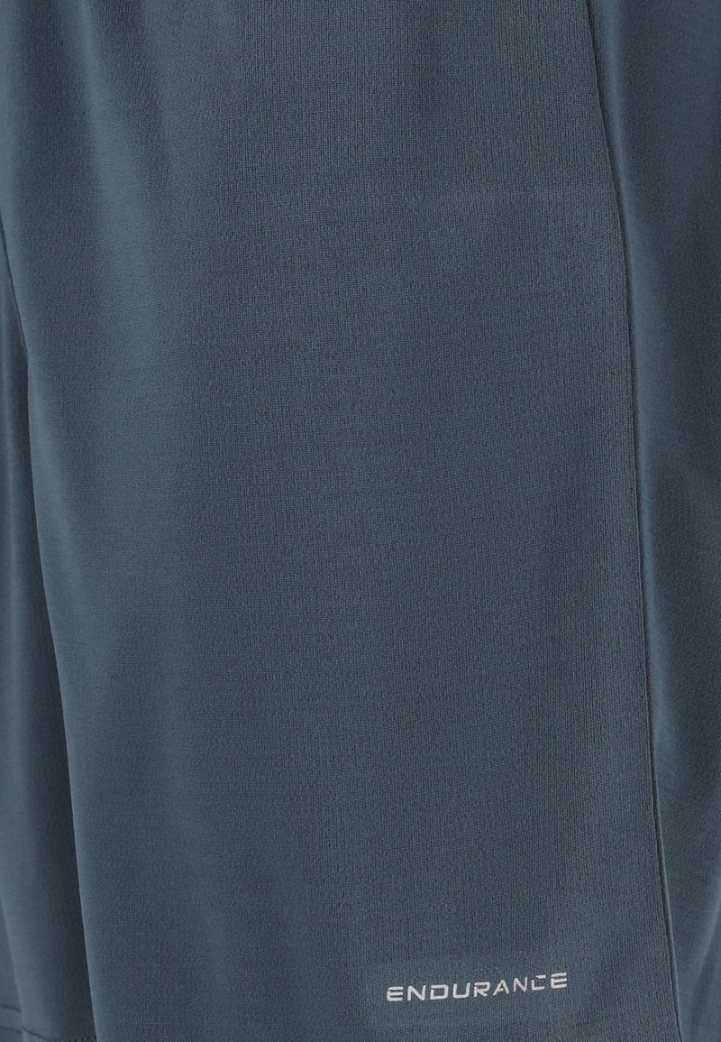 Marinblå sportshorts tillverkade av ett mjukt, lättviktsmaterial med en subtil textur och logotypen "ENDURANCE" i vitt.