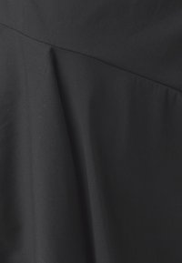 Černý oděv s hladkým povrchem, který má na lemu nařasenou látku a jemný šev v horní části.