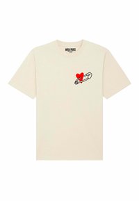 T-shirt en coton crème avec un contour noir d'une épingle de sûreté tenant un cœur rouge sur la zone gauche de la poitrine. Manches courtes, col rond.