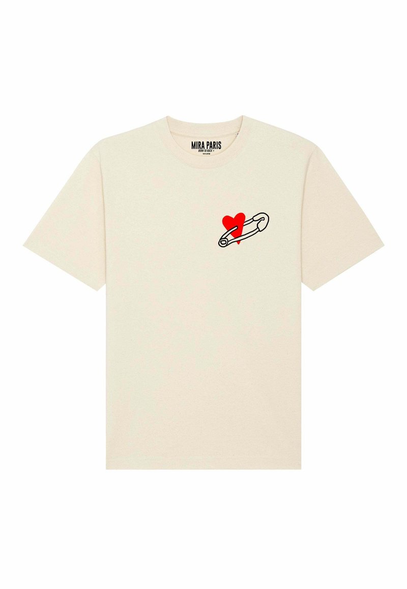 T-shirt en coton crème avec un contour noir d'une épingle de sûreté tenant un cœur rouge sur la zone gauche de la poitrine. Manches courtes, col rond.