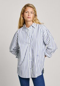 Camicia a righe bianca e blu. Presenta un colletto, maniche lunghe e una vestibilità rilassata. Il tessuto appare leggero con una consistenza liscia.