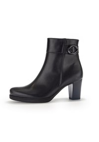 Botte noire en cuir jusqu'à la cheville avec un bout rond, un haut talon bloc et un accent circulaire décoratif sur le côté. Texture lisse et design simple.