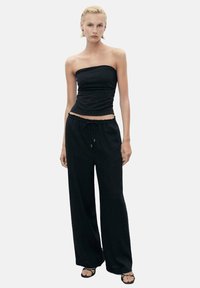 Black strapless top paired with loose-fitting black pants, featuring an elastic waistband and drawstring. Lightweight fabric with a smooth texture.