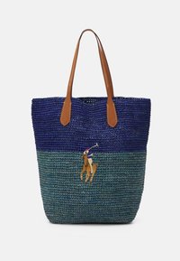 Vävd toteväska i blått och grönt, med bruna läderhandtag och en broderad polo spelare på häst som en anmärkningsvärd detalj.