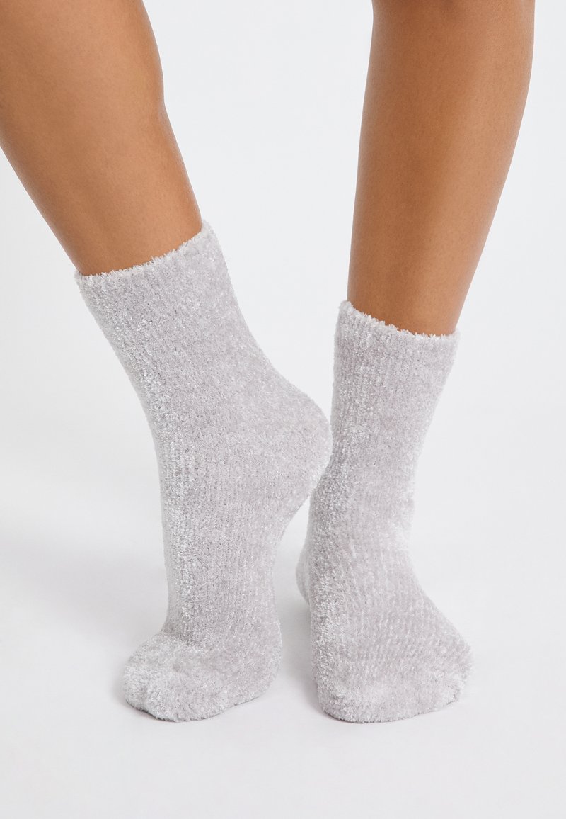 Graue, flauschige Socken mit weichem Material und gerippten Bündchen, in mittlerer Wadenhöhe und mit runden Zehen, geeignet für den Alltag.