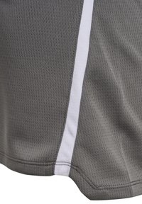 Grauer atmungsaktiver Mesh-Stoff mit kleinen Perforationen und einem vertikalen weißen Streifen als Akzent am Saum eines Kleidungsstücks.