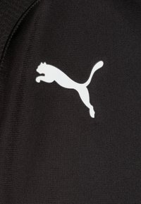 Crni materijal s teksturiranom površinom sadrži bijeli Puma logo skakutave mačke, istaknuto prikazan na desnoj strani.
