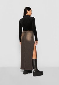 Long brown denim skirt with a side slit, paired with black knee-high platform boots. The top is a fitted black long-sleeve shirt.