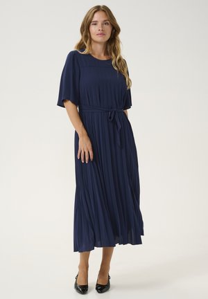 Navy pleated dress with short sleeves, a round neckline, a belted waist, and a flowing silhouette. Material appears smooth and lightweight.