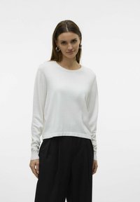 Maglietta bianca a maniche lunghe in knit con scollatura rotonda e polsini a coste, caratterizzata da una vestibilità rilassata e una finitura liscia e leggermente texturizzata.