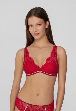 El sujetador de encaje rojo presenta un escote pronunciado, bordes en forma de ondas, tirantes anchos y una banda bajo el busto con detalles plateados.
