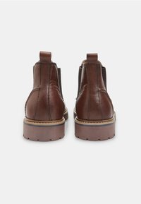 Pruunid nahast Chelsea saapad, millel on venituspaneelid külgedel ja tõmbenöörid. Paksemad kummitaldad on varustatud tekstuuriga mustriga, mis tagab hea haardevõime ja vastupidavuse.