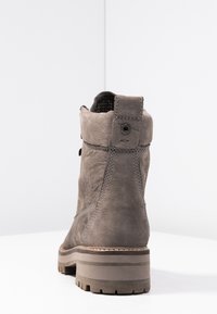 Grå läderankelstövel med en texturerad yta, tjock sula och förstärkt klack. Har framträdande sömmar och en ögla för enkel påtagning.