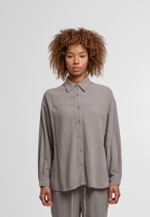 Gray long-sleeve button-up shirt made from soft fabric, featuring a collar, front buttons, and a relaxed fit. Slightly curved hemline.