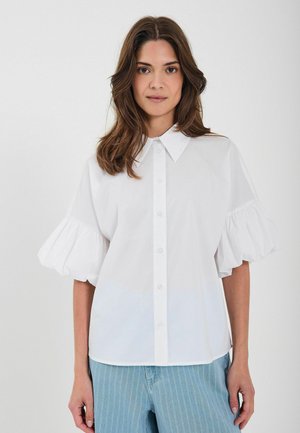 Hvid skjorte med puffede ærmer, knaplukning og glat tekstur. Sammen med blåstribede bukser for et afslappet look.