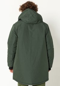 Groene waterdichte jas met een capuchon, voorzien van een gladde textuur, lange snit, elastische manchetten en zijzakken, ontworpen voor koud weer.