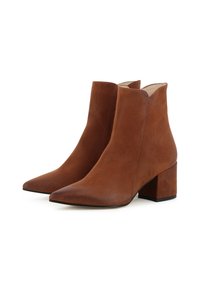Bottines en cuir suédé marron avec un bout pointu, un petit talon carré et une texture lisse. Présentent des lignes épurées et un bord supérieur en forme de vague.