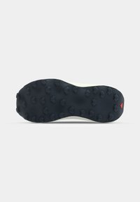 Semelle en caoutchouc noir avec des crampons multidirectionnels pour une meilleure traction, dotée d'un milieu de semelle blanc et d'un petit accent rouge au niveau du talon.