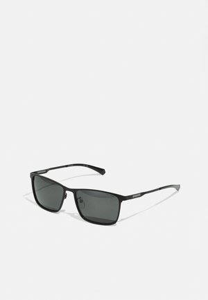 Óculos de sol retangulares pretos com lentes escuras. Armação em metal, hastes finas e detalhes discretos nas têmporas. Textura suave em toda a sua extensão.