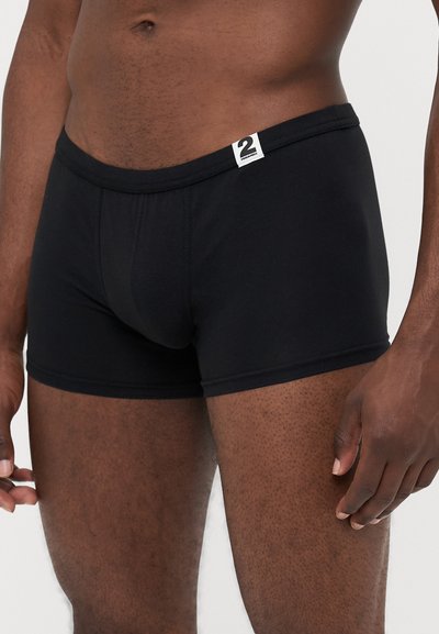 Schwarze Baumwoll-Boxershorts mit glatter Textur, die einen weichen Bund und ein kleines Etikett auf der Vorderseite haben. Enganliegender Stil, Oberschenkel-lange.
