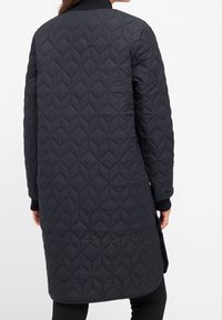 Prošívaná černá bunda s dlouhou siluetou, žebrovanými manžetami a vysokým límcem. Texturovaný diamantový vzor po celé látce.