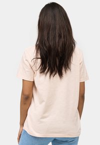 Jasnoróżowa koszulka z krótkim rękawem o luźnym kroju, wykonana z miękkiej bawełny, z prostym wzorem i okrągłym dekoltem.