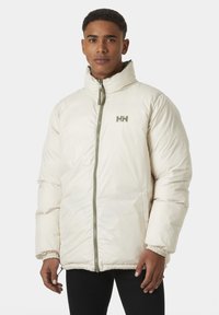 Přefukovací bunda v off-white barvě s zelenými akcenty. Má vysoký límec, zipový uzávěr, elastické manžety a logo na hrudi.
