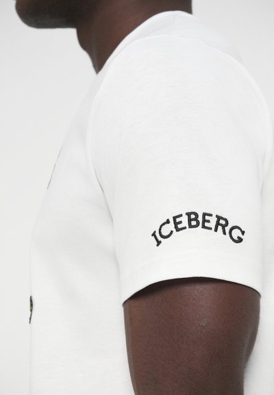 Λευκό βαμβακερό T-shirt με κοντά μανίκια και στρογγυλή λαιμόκοψη. Διαθέτει μαύρο κεντητό κείμενο "ICEBERG" στο αριστερό μανίκι.