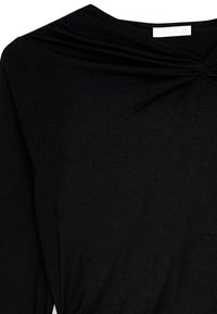 Juodas ilgomis rankovėmis viršus, pagamintas iš minkštos medžiagos, su sukimo mazgo detale ant kaklo, kuri sukuria tekstūruotą išvaizdą.