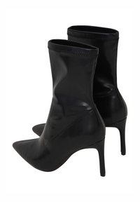 Czarne botki za kostkę wykonane z gładkiej skóry, z ostrym noskiem i cienkim obcasem typu stiletto; cholewka charakteryzuje się bezszwowym wzornictwem oraz elastycznym wykończeniem na górze.