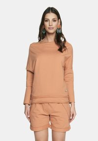 Jasnopomarańczowa bluza z dekoltem w łódkę i długimi rękawami, w zestawie z dopasowanymi szortami z podwiniętymi nogawkami i bocznymi kieszeniami.