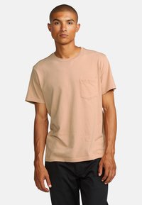 Cotton short-sleeve t-shirt in light peach with a crew neckline and a left chest pocket. Smooth texture and relaxed fit.