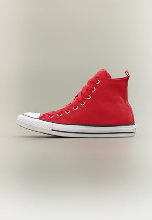 Rode hoge sneaker met witte rubberen zool en neuskap, metalen veterogen en bijpassende rode veters, zijaanzicht op een neutrale achtergrond.