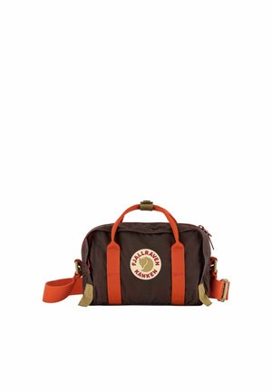 Kleine rechteckige dunkelbraune Fjällräven Kånken Tasche mit orangefarbenen Griffen und Schulterriemen sowie einem runden Logo auf der Vorderseite.