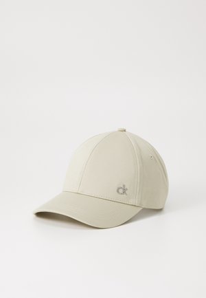 Beige baseball cap with a smooth fabric, rounded crown, curved visor, and a small silver logo on the front left side.